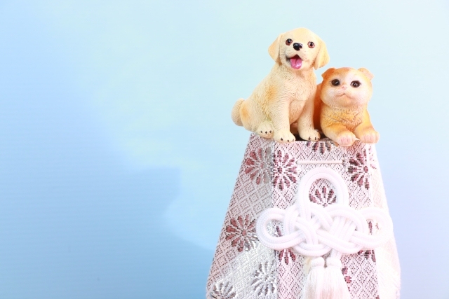 骨壺の上に座る犬と猫の置物